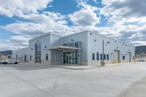 Government steel building used as a modern police department with large glass entrance, multiple garage bays, and police vehicles parked outside
